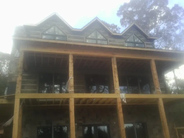 Dormers and porch framing on a large log home under construction — Roof Coating work by our crew in Defiance